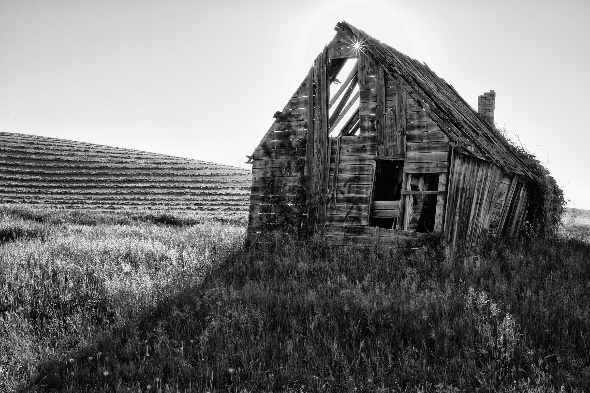 Historic weathered timber farmhouse under expansive western skies in Idaho