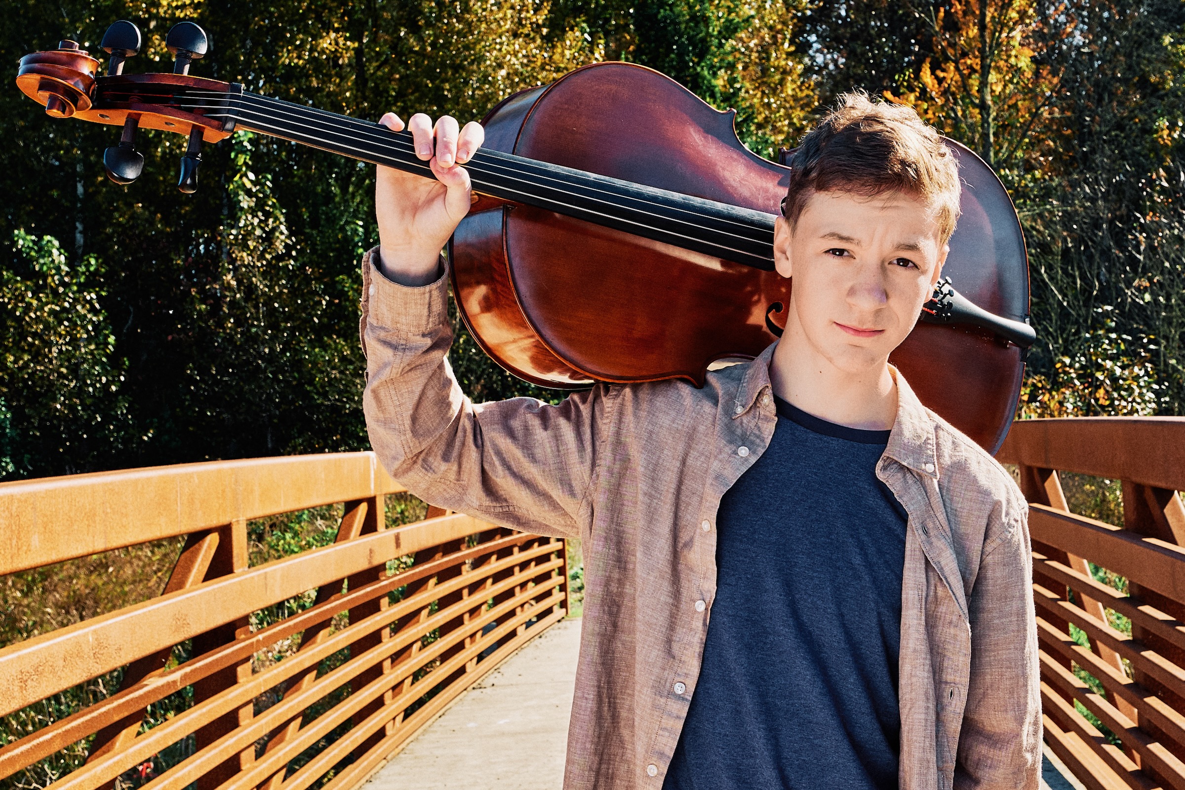 High school senior cellist carrying his instrument on a bridge in Vancouver Washington